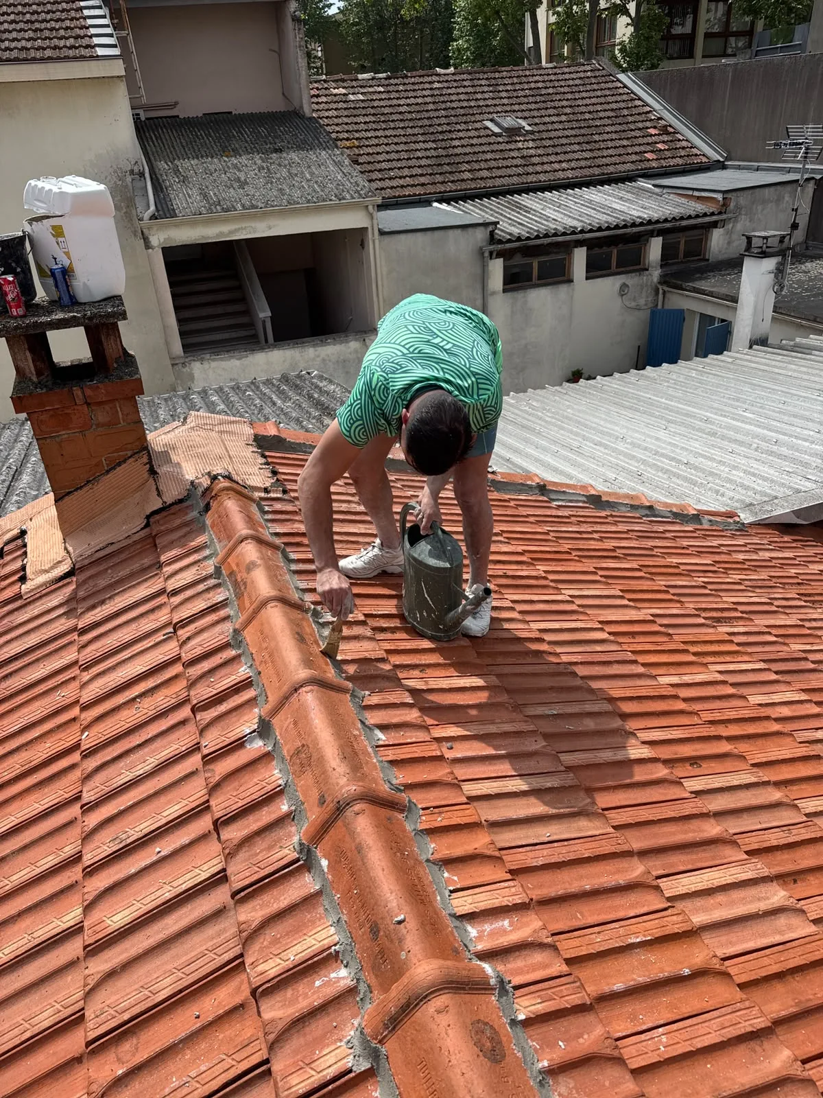 Couvreur intervenant sur les tuiles au voisinage du faîtage